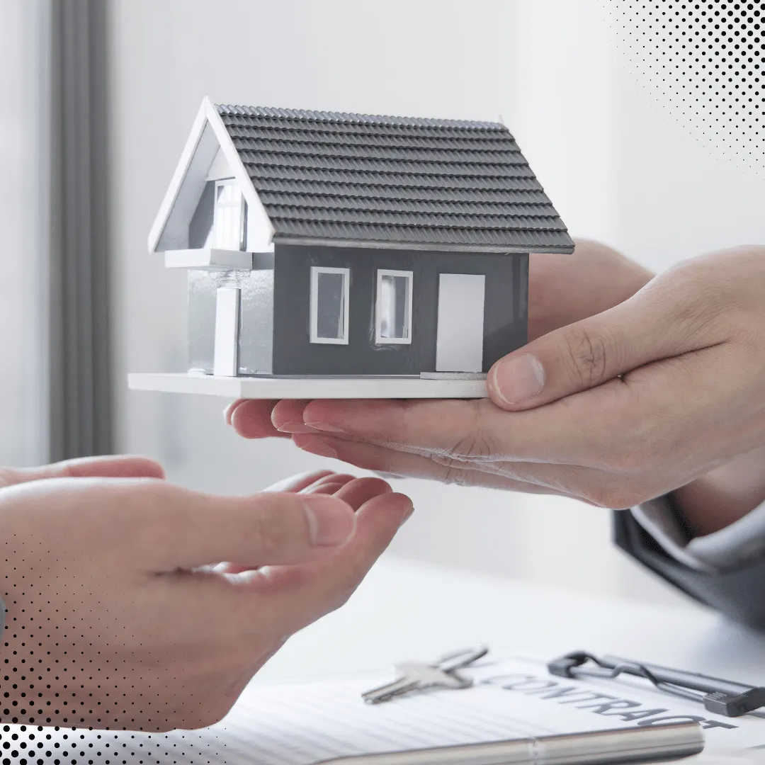 Hands holding a miniature house model during a home inspection consultation