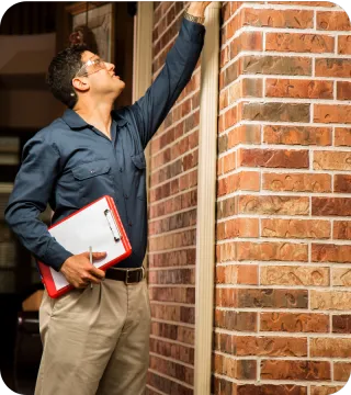 Home inspector examining a brick exterior with clipboard in hand — representing thorough, professional home inspections in Orlando, FL.