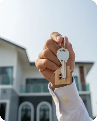 Person holding house-shaped keychain in front of a modern home, symbolizing professional pre-listing home inspection in Orlando.