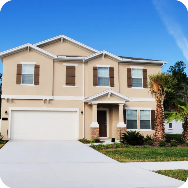 Two-story beige home in Deltona, Florida with palm trees and a driveway under a clear blue sky, representing homes inspected by A.C.F. Home Inspections.