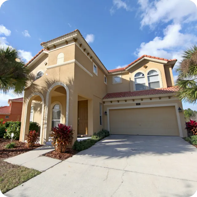 Two-story tan-colored home in Clermont, Florida with palm trees and a two-car garage, representing residential properties inspected by A.C.F. Home Inspections.