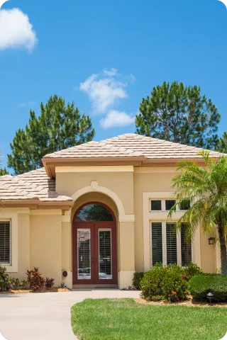 Beige stucco home in Deltona, Florida with arched entryway, palm trees, and manicured lawn under a blue sky, representing inspected Central Florida homes.