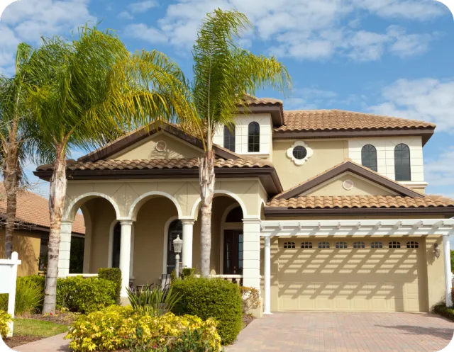 Tan stucco home in St. Cloud, Florida with palm trees, arched entryway, and double garage under a blue sky, representing inspected Central Florida homes.