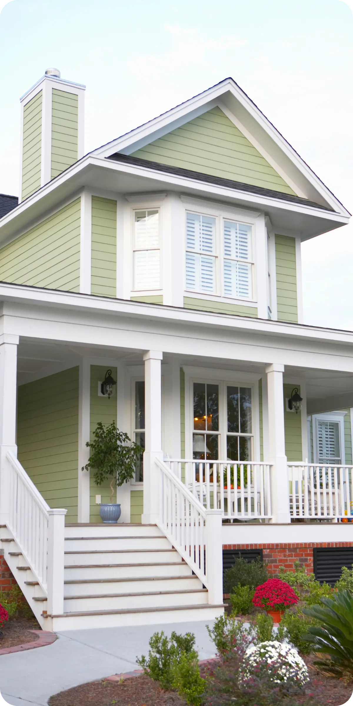 Front exterior of a light green two-story home with white trim and covered porch in Orlando, FL, representing a newly built house for an 11-month builder warranty inspection.
