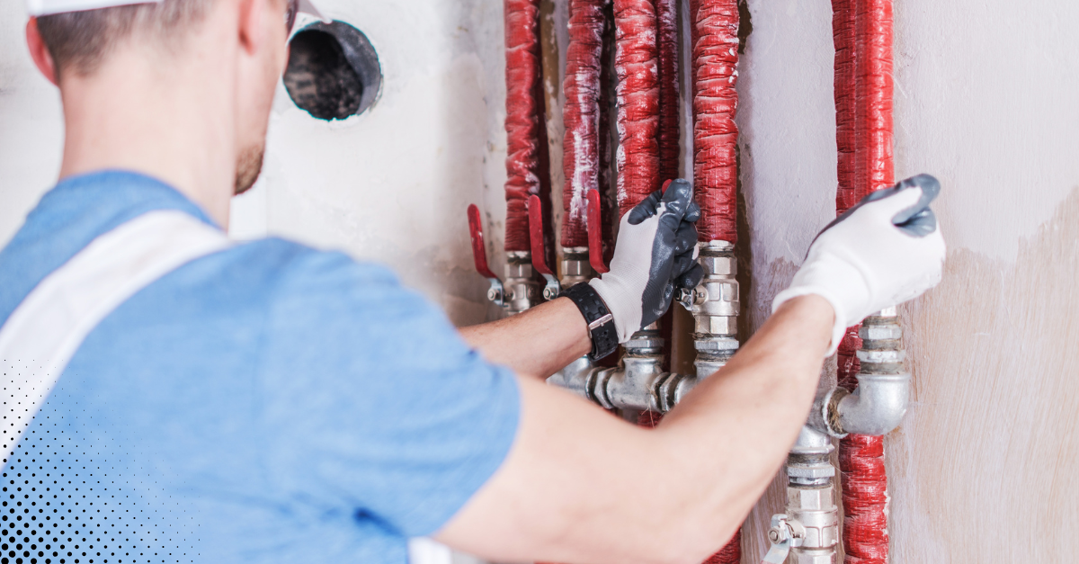 Technician inspecting red water pipes inside wall